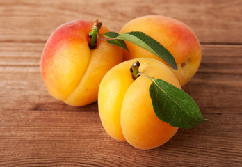Fresh apricot with leaf on a wooden board.
