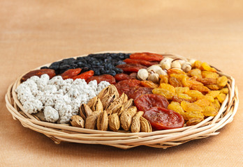 Dried fruits and nuts in a wicker dish on a fabric surface