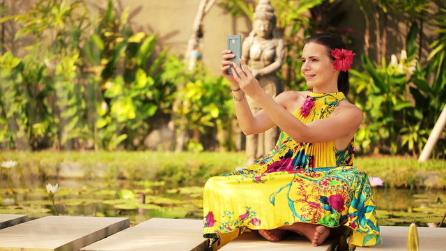 Attractive woman taking photo with cellphone in exotic garden
