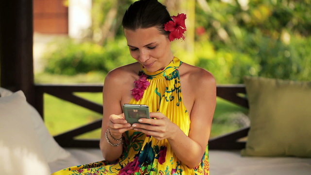 Attractive woman texting on smartphone, relaxing in gazebo bed
