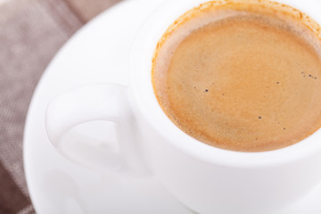White cup of coffee on tablecloth