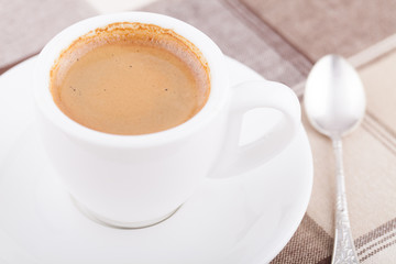White cup of coffee on tablecloth