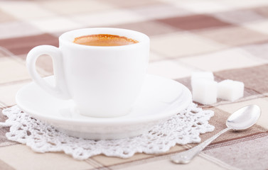 White cup of coffee on tablecloth
