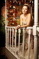 Young beautiful woman in vintage dress on autumn porch. Beauty g