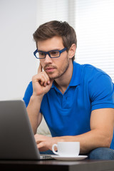 handsome young man working on computer laptop at home.