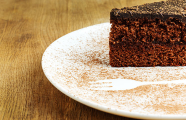 Piece of chocolate cake in a white plate with cocoa powder