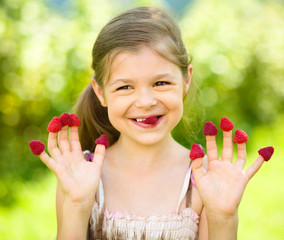 Young girl is holding raspberries on her fingers