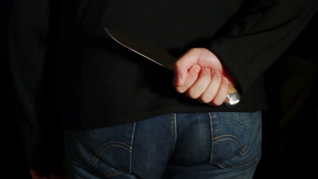 Man with a knife behind his back goes back frame