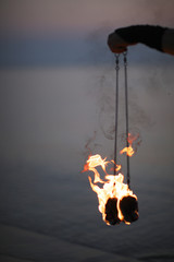 Pair of burning poi in firedancer hand