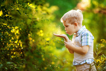 Little boy blows gold glitter from his hands.