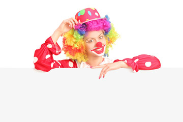 Female clown standing behind a blank panel
