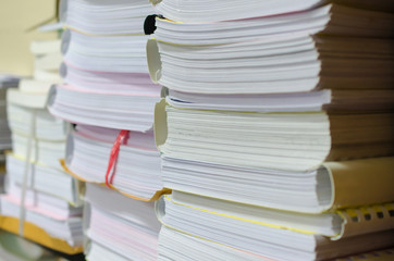Pile of documents on desk stack up high waiting to be managed.
