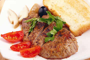 serving of meat with vegetables on a plate of white background