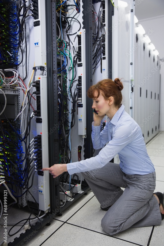 Poster serious technician talking on phone while analysing server