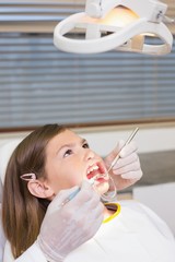 Dentist using mouth retractor on little girl