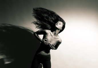 Obraz premium Beautiful girl with flowing hair on a gray background.