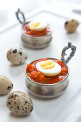 Hard boiled quail eggs with tomato sauce