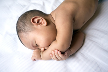 Cute Asian baby boy sleeping on a white bed