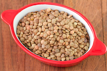 lentil in red dish on brown background