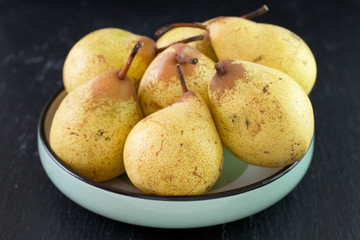 yellow pears in bowl on black background