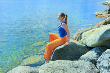 girl sits on bank of lake