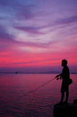 Fototapeta premium Silhouette of fishing man beside the sea