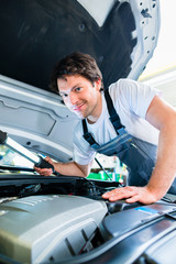 KFZ-Mechaniker arbeitet in Autowerkstatt