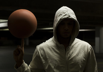 Anonymous street ball basketball player spinning a ball at night