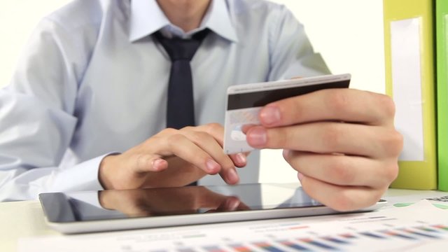 Business man paying with credit card by tablet.
