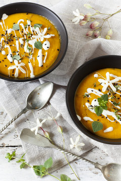 cream of pumpkin and carrot soup on two bowls with sour cream