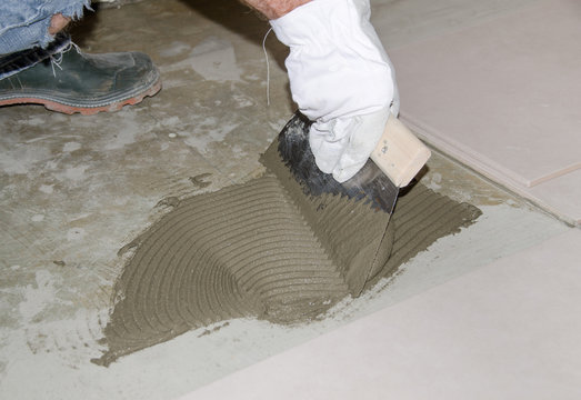 Tiler spreading tile adhesive on the floor