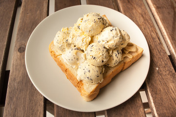 Ice cream on a slice of bread on woodden table