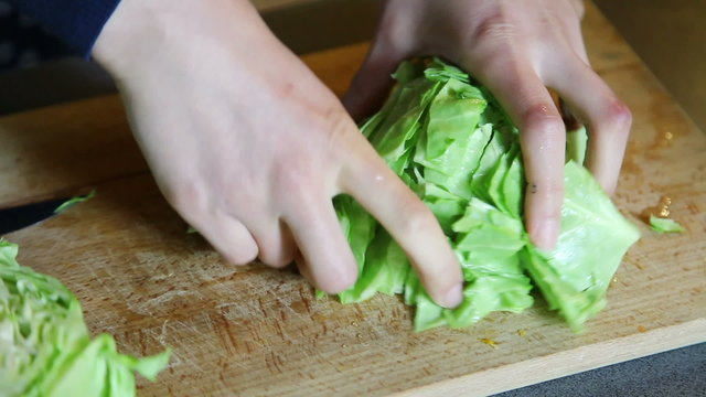 Hands cutting cabbage on wooden board