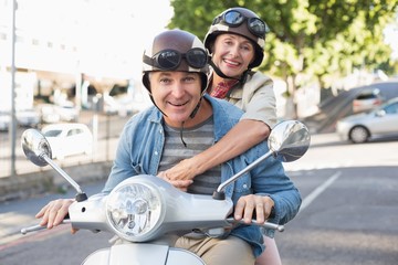 Naklejka premium Happy mature couple riding a scooter in the city