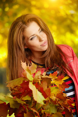 Naklejka na ściany i meble Beautiful elegant woman in a park in autumn