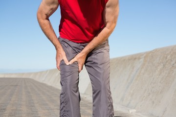 Active senior man touching his injured thigh