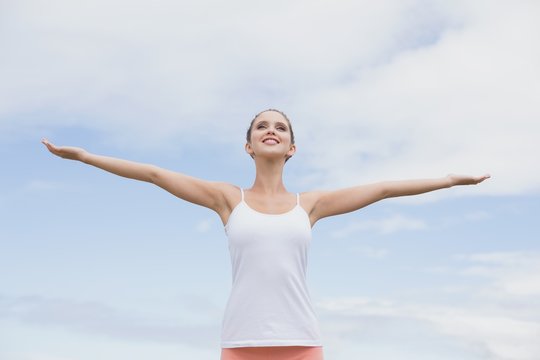 Beautiful woman with arms raised against the sky