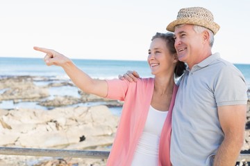 Happy casual couple looking at something by the coast