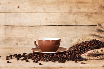 Kaffeetasse mit Kaffeebohnen und Leinensack vor vintage Holz