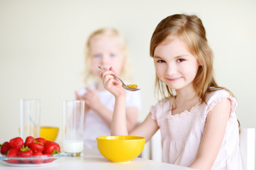 Two sisters eating cereal with milk