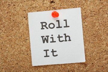 The phrase Roll With It on a cork notice board