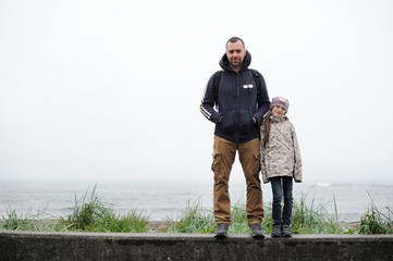 Father and daughter on the beach in rainy day.