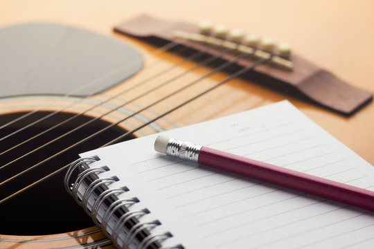 Notebook and pencil on guitar