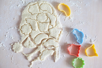 Thin dough on table with colorful plastic cake molds, raw cookie