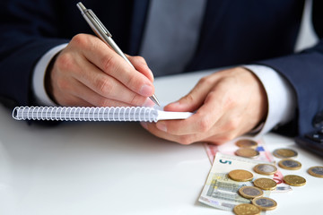 Businessman hand holding a pen writing on notepad
