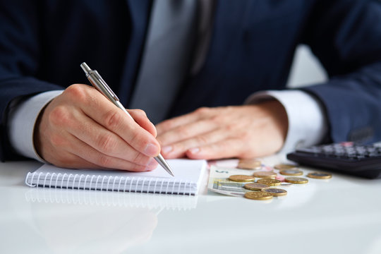 Businessman hand holding a pen writing on notepad