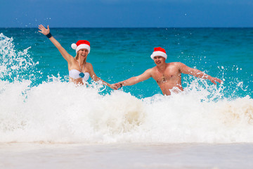 Young beautiful couple in love having fun in the waves dressed i