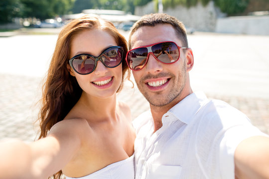 smiling couple wearing sunglasses making selfie