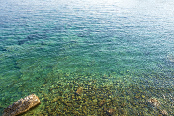 Naklejka na ściany i meble Clean clear sea water and pebbles on the beach