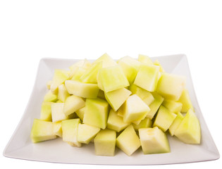 Bite sized honeydew pieces on white plate © akulamatiau